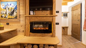 Ein Kamin aus Holz mit Holzablage darunter, ein an der Wand befestigter Fernseher und ein Gemälde.