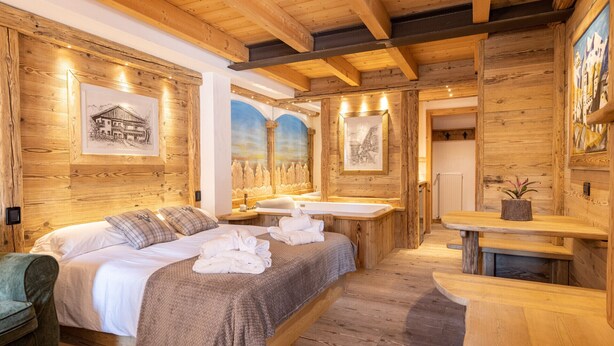 Ein schlicht eingerichtetes Schlafzimmer im Chalet-Stil mit einem Bett, einer Bank und einem kleinen Tisch.