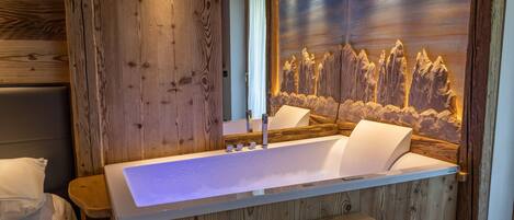A wooden spa area with a large bathtub, wooden benches, and a wall mural of mountains.