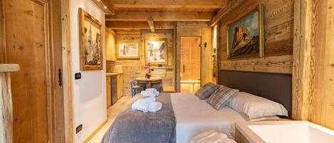 A cozy wooden room with a bed, a small table, and a sink.