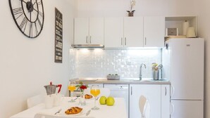 A modern kitchen with white cabinets, a clock, and a dining table set with breakfast items.