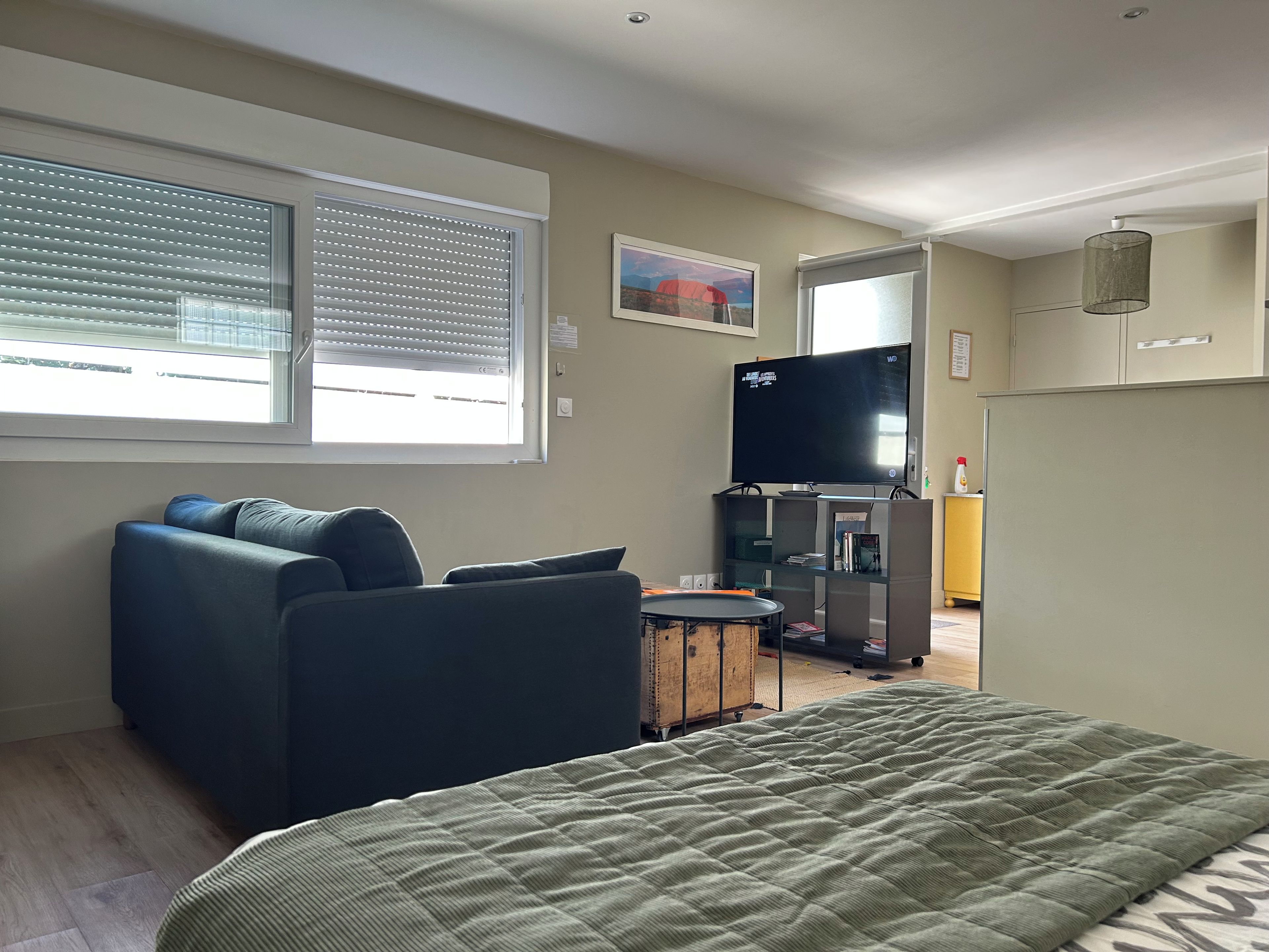 A modern living room with a sofa, a television, and a bed.