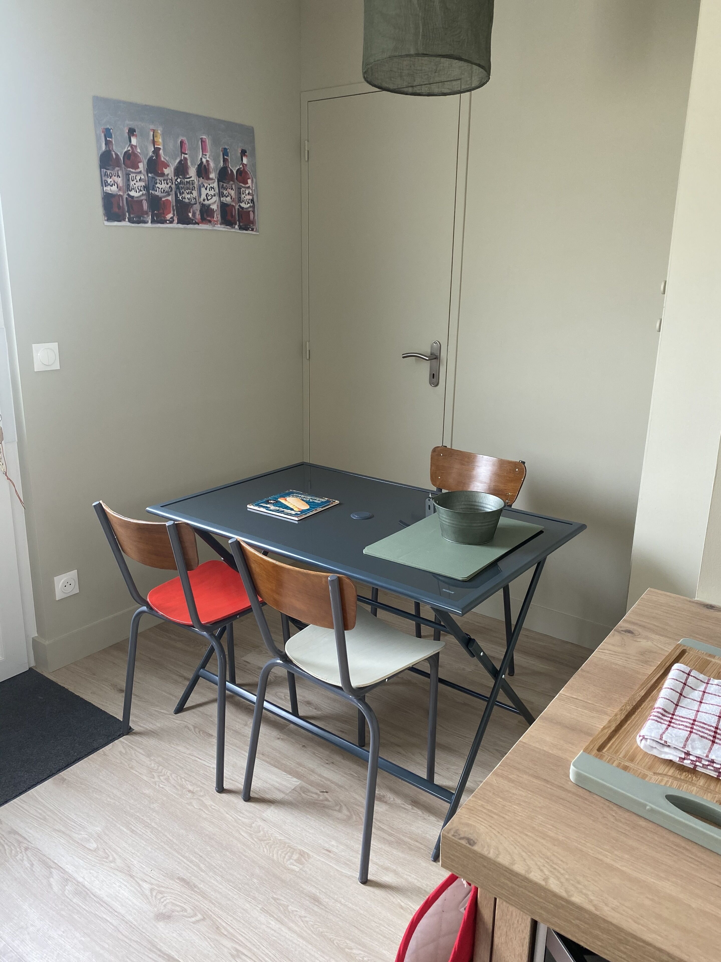 Un coin repas comprenant une table, des chaises, un tableau et une porte.