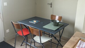 A dining area with a table, chairs, a painting, and a door. - Studio Bordeaux 2 (Bordeaux)