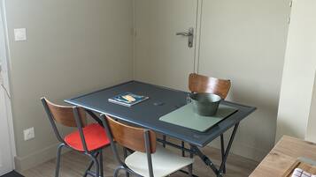 Un coin repas comprenant une table, des chaises, un tableau et une porte.