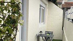 A small outdoor patio with a table and chairs, surrounded by a white wall and a green artificial turf area. - Studio Bordeaux 2 (Bordeaux)