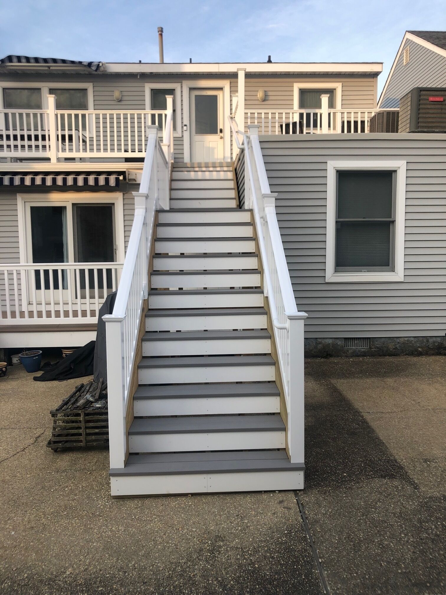 A residential building with a central staircase leading to a front door, surrounded by a white railing.