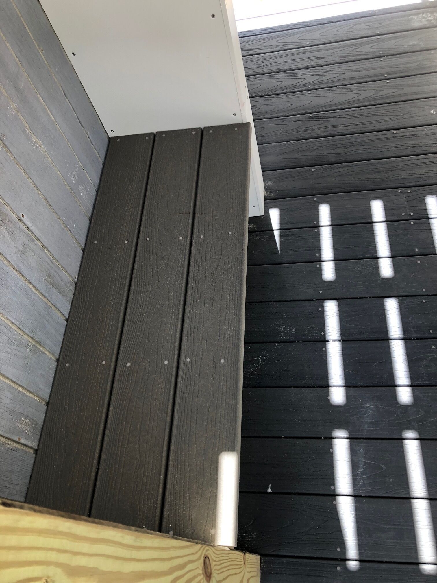 Een houten terras met een witte reling en een donker houten vloer.