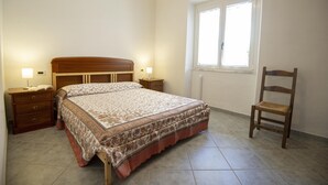 A bedroom with a bed, bedside tables, a chair, and a window. - Discount for the period January -May 2023 (Cala Gonone)