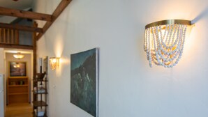 A hallway with a wooden ceiling, a wall-mounted light fixture, and a framed painting.