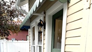 A narrow stone pathway leading to a house with a green door and white-framed windows.
