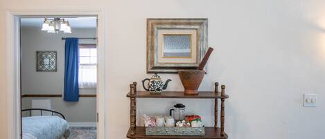 A bedroom with a bed, a dresser with decorative items, a framed picture on the wall, and a window with curtains.