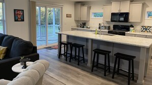 A modern kitchen with a central island, white cabinets, and a black microwave.