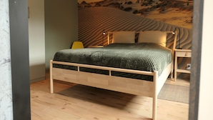 A bedroom with a wooden bed, a nightstand, and a wall mural of a desert landscape.