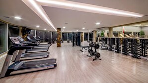 A gym with treadmills, weight machines, and a mirrored wall. - Laghetto Resort Golden (Gramado)