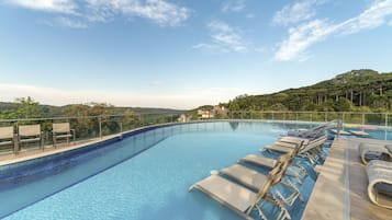 Una piscina techada, una piscina al aire libre, sombrillas