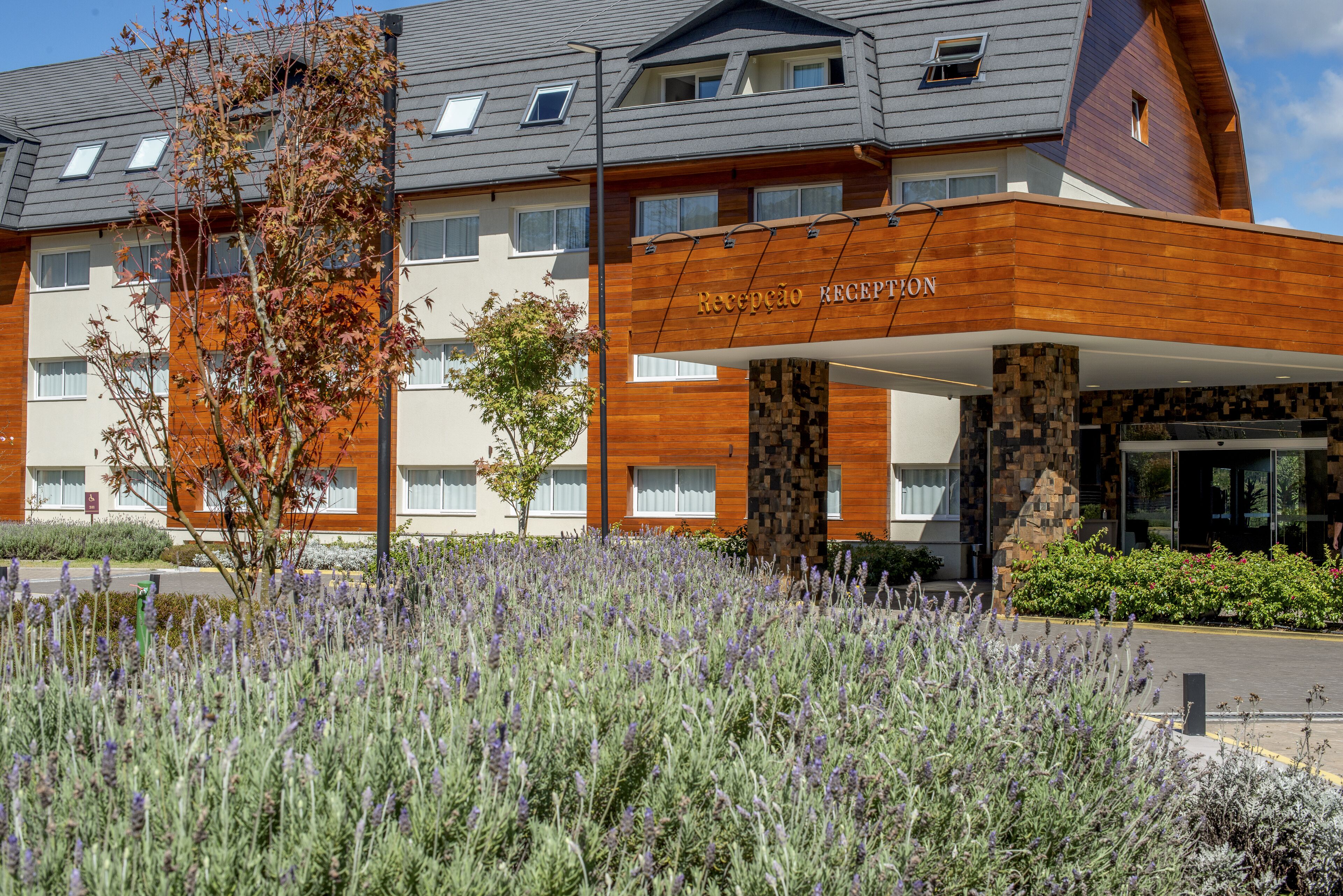 Un hôtel doté d’un espace de réception, d’une façade moderne et d’un jardin aménagé avec des plantes de lavande.