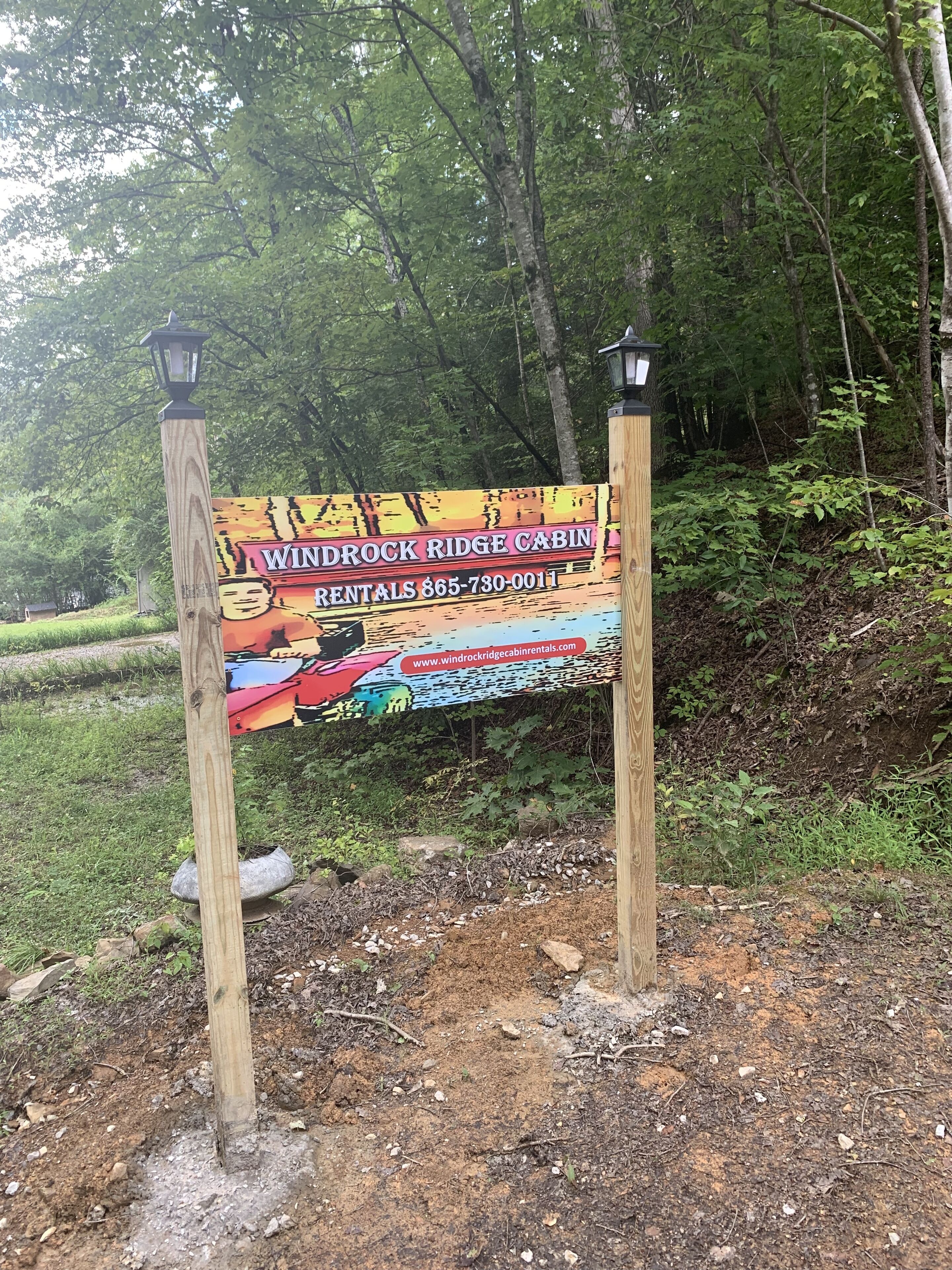 Un panneau en bois, agrémenté d’un graphisme coloré et d’un texte publicitaire pour les locations de chalets de Windrock Ridge, avec indication d’un numéro de téléphone et d’une adresse de site web.