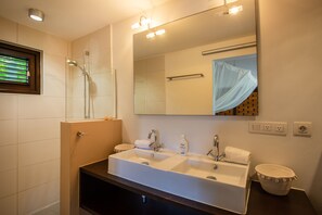 A bathroom with a double sink, a glass-enclosed shower, and a large mirror. - Blue Bay Bungalows - The Garden (Sint Michiel)