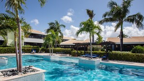 Un área de piscina con varias piscinas, palmeras y sillas de descanso.