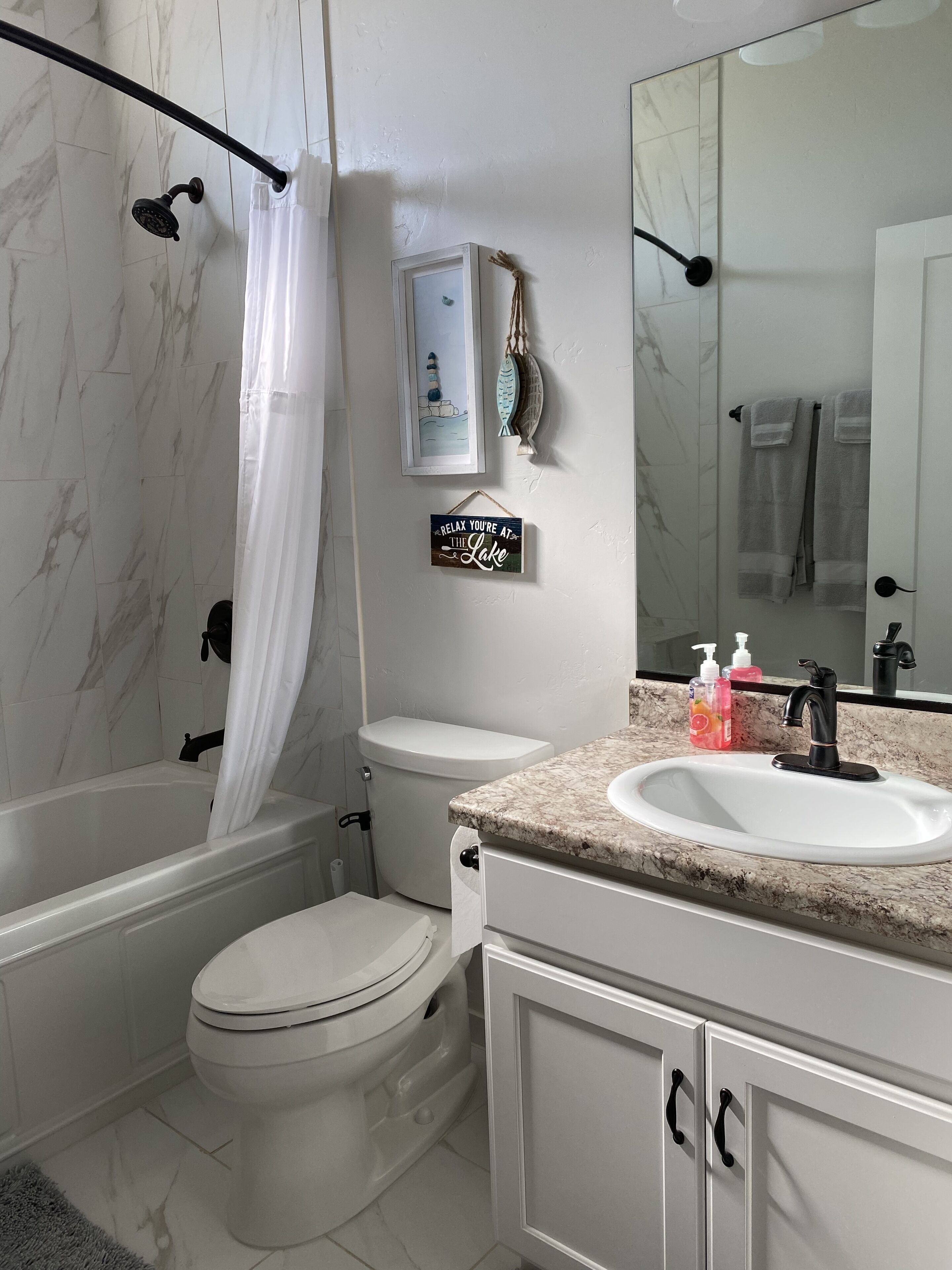 A bathroom with a bathtub, toilet, sink, and a large mirror.