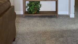 Un salón con un sofá marrón, una consola de madera con cajones, un cuadro de un puente y una planta pequeña.