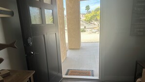 Una puerta de madera oscura que da a un espacio al aire libre cubierto, con vistas a un paisaje desértico.