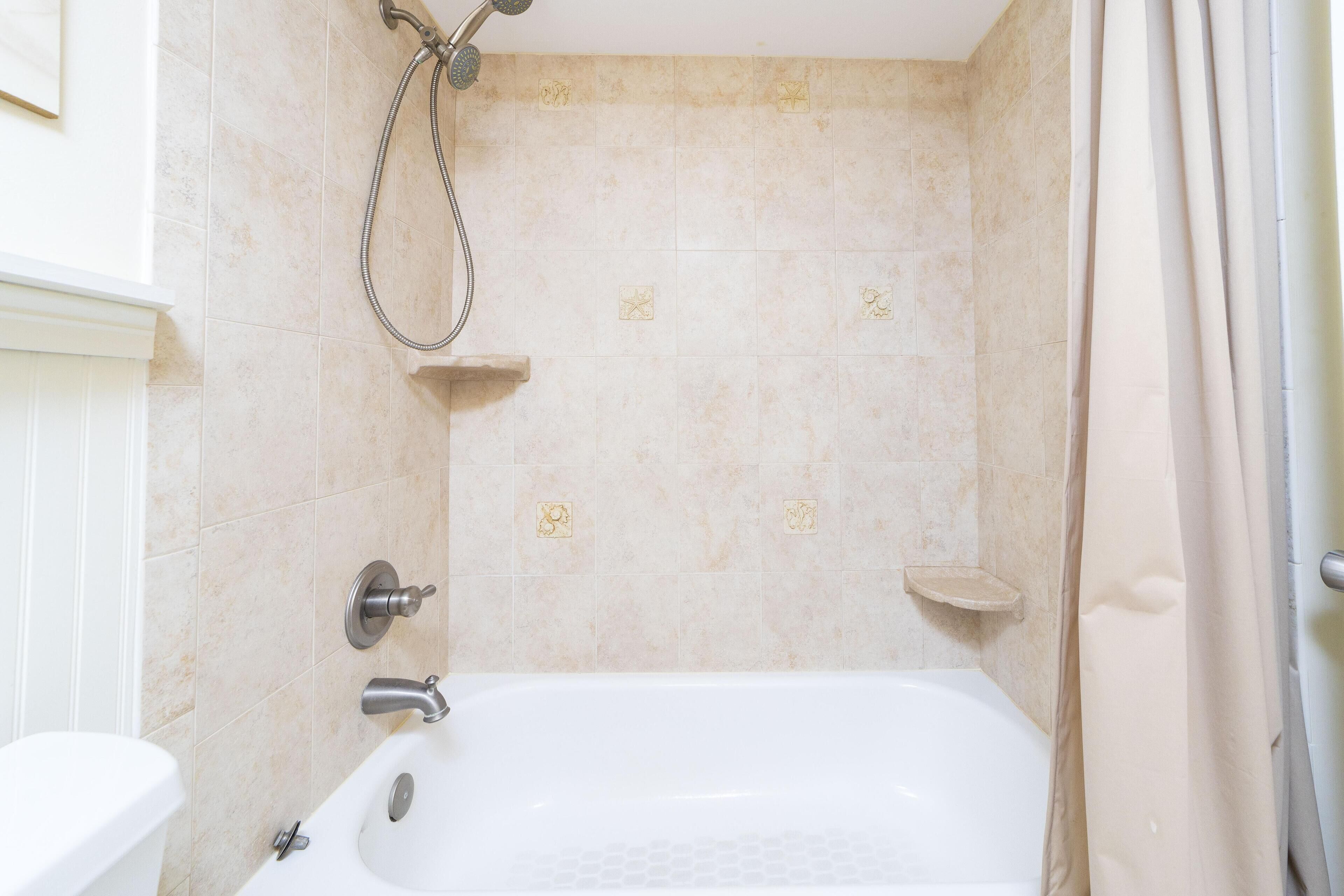 A bathroom with a bathtub, shower, and toilet.