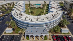 Un grande hotel a forma di cerchio con un cortile centrale, numerosi balconi e una zona piscina.