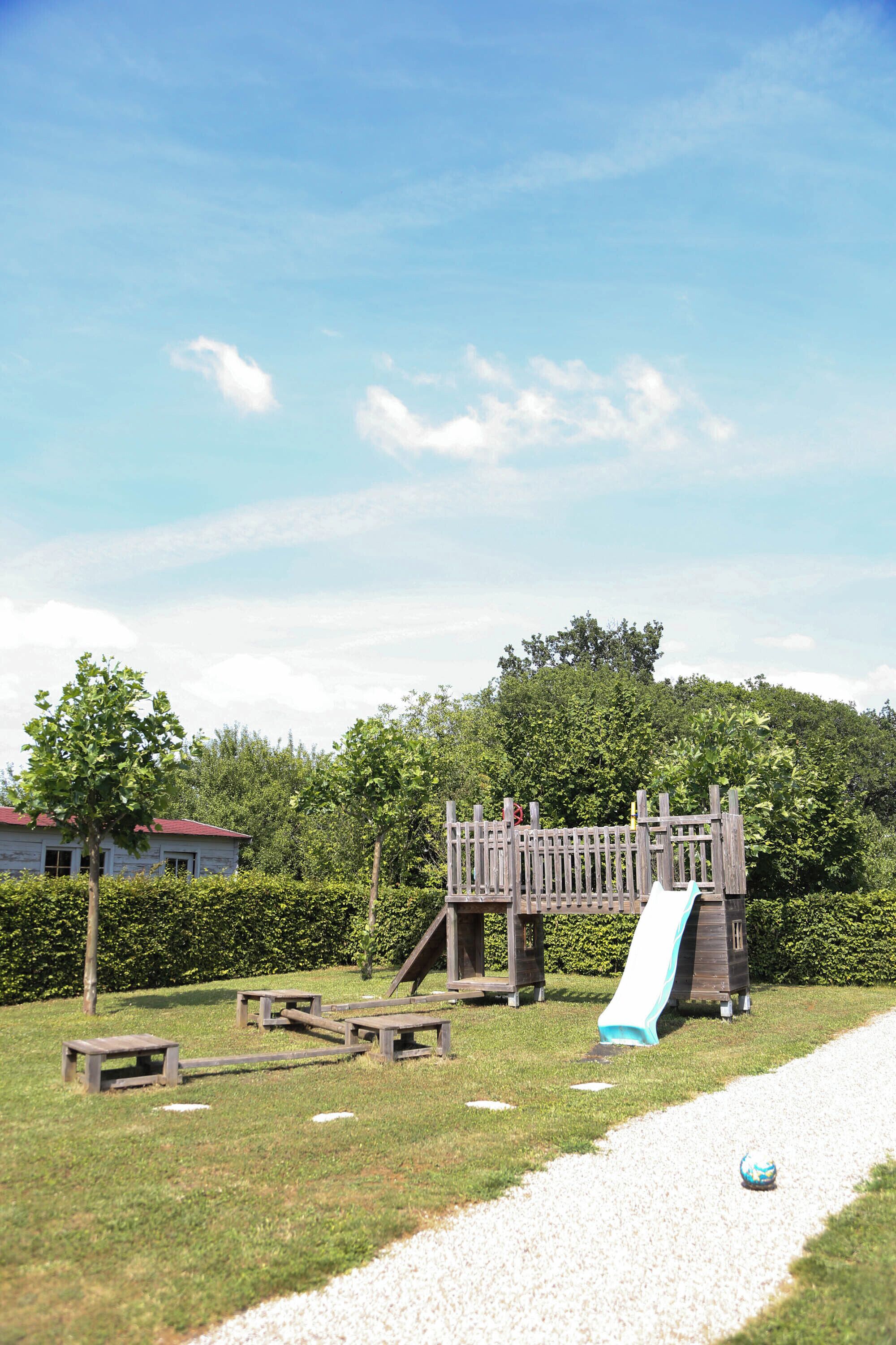Un parque infantil con un tobogán y mesas de picnic.