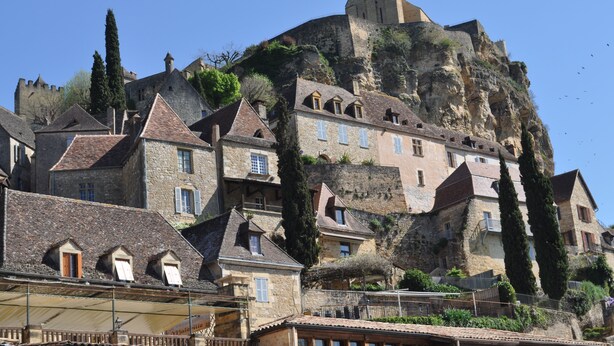 Un bâtiment historique en pierre, à plusieurs niveaux, doté de toits à forte pente et d’une tour imposante.