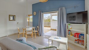 Un salon comprenant un canapé, une table, des chaises, un téléviseur et une bibliothèque.