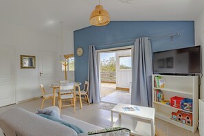 A living room with a sofa, a table, chairs, a television, and a bookshelf. - Gîte Bellevue   (JAYAC)