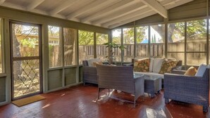A covered patio with wicker furniture, a dining table, and a view of a backyard. - 6 Bedrooms in #1 Central Location (Austin)