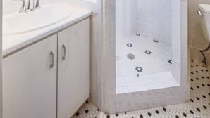 A modern bathroom with a white sink, mirror, and shower enclosure. - 6 Bedrooms in #1 Central Location (Austin)