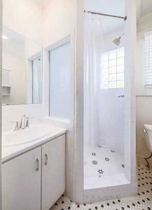 A modern bathroom with a white sink, mirror, and shower enclosure. - 6 Bedrooms in #1 Central Location (Austin)