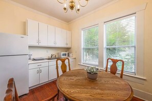 A kitchen with white cabinets, a microwave, and a sink. There is a dining table with chairs and a potted plant. - 6 Bedrooms in #1 Central Location (Austin)