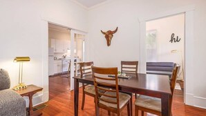 A dining area with a wooden table, four chairs, a bull's head decoration, and a wall with a 'hu' sign. - 6 Bedrooms in #1 Central Location (Austin)