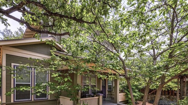A two-story house with a covered porch, a small front yard, and a tree in front. - 6 Bedrooms in #1 Central Location (Austin)