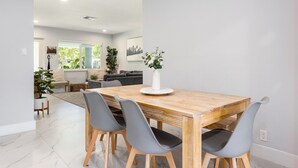 A dining area with a wooden table, four grey chairs, and a white vase with flowers. - !! Modern & Stylish Fort Lauderdale Getaway !! (Fort Lauderdale)