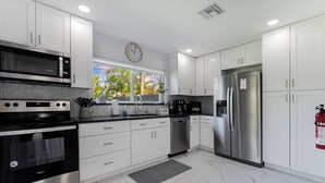 A modern kitchen with white cabinets, stainless steel appliances, and a clock on the wall. - !! Modern & Stylish Fort Lauderdale Getaway !! (Fort Lauderdale)