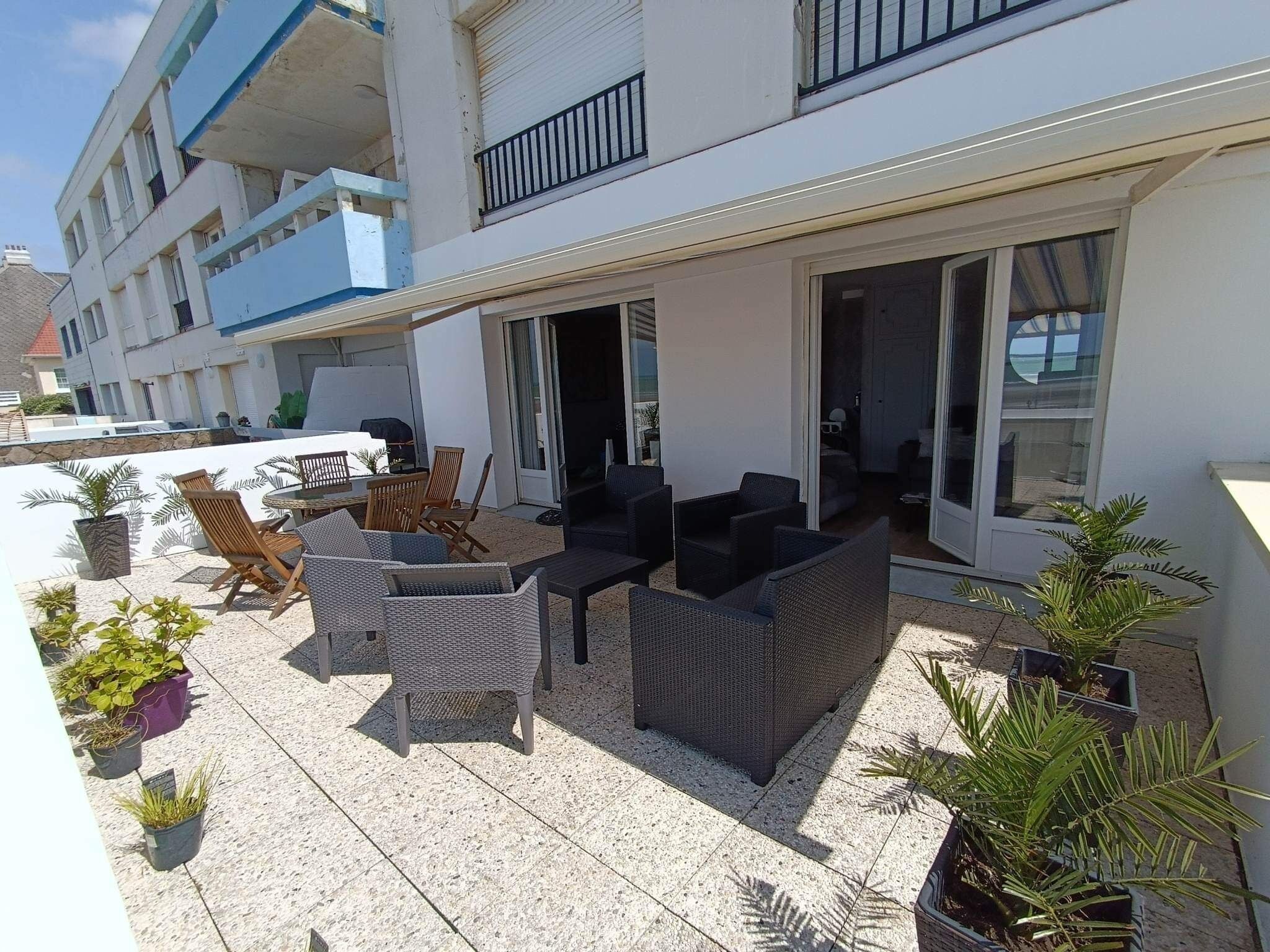 A terrace with outdoor furniture, potted plants, and a view of the building's interior.