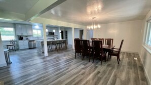 A spacious kitchen with modern appliances, a dining area with wooden chairs, and a large window providing natural light.