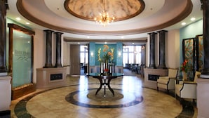 Eine Lobby mit einem runden Tisch in der Mitte, Säulen und einer Chandelier.