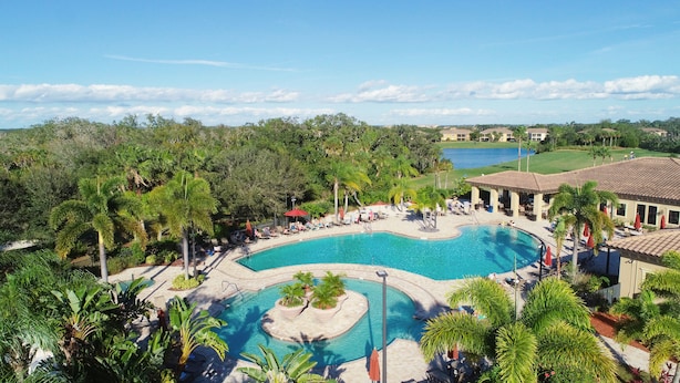 Ein Resort mit großem Pool, Palmen und einem Golfplatz im Hintergrund.
