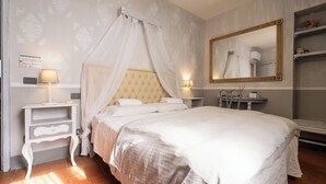 A bedroom with a large bed, a bedside table, a chair, a mirror, and a wall with a decorative pattern.
