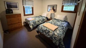 Un dormitorio con dos camas, un aparador, una lámpara y un televisor en la pared.