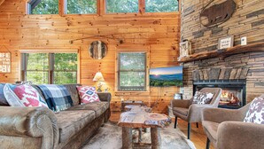 L’intérieur chaleureux d’un chalet avec un plafond en bois, une cheminée, un canapé et une table basse.