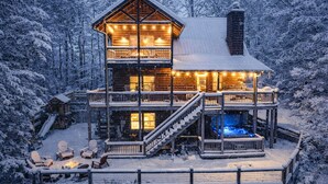 Une cabane en rondins avec un balcon au deuxième étage et un jacuzzi au niveau du rez-de-chaussée.