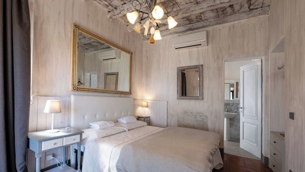 Ein Schlafzimmer mit einem großen Bett, zwei Nachttischen, einem Spiegel und einer Chandelier.